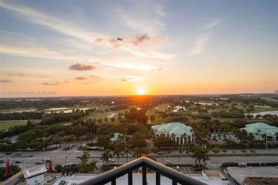 Panoramic view of a green landscape with buildings at sunset.