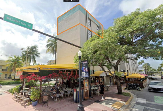 Street view of a building with outdoor dining area and yellow awnings.