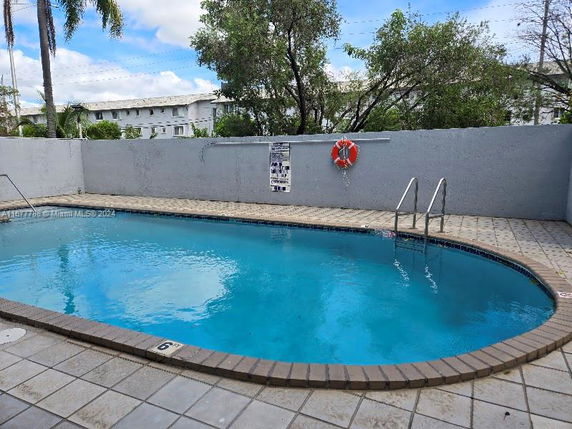Outdoor swimming pool with surrounding fence and safety equipment.