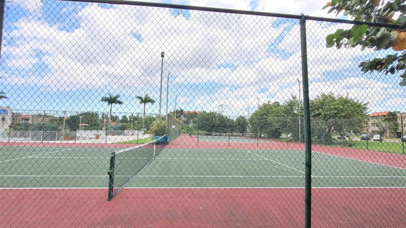 Tennis court with surrounding chain-link fence.