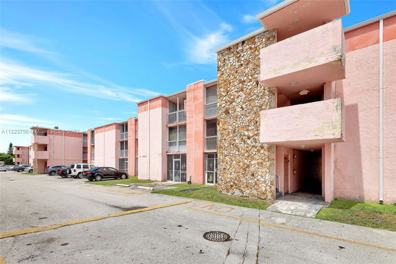 Front view of a multi-story pink residential building with balconies and stone accents.