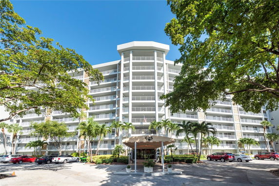 Front view of a multi-story residential building with balconies and a covered entrance.