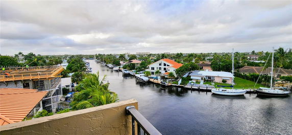 Panoramic view from a building overlooking a canal with boats and residential houses.