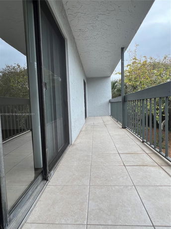 View of a tiled balcony with railing and sliding glass doors.