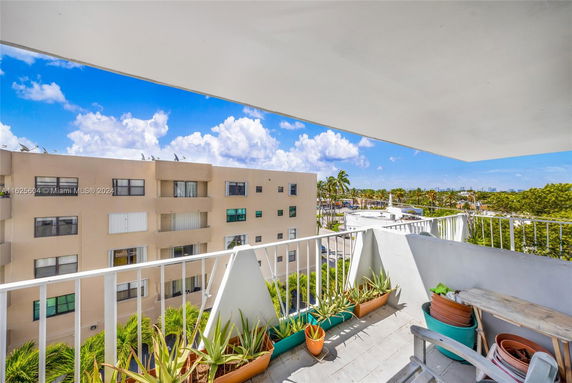 View from a balcony overlooking surrounding buildings and palm trees.