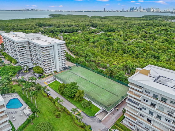 Aerial view of residential buildings with tennis courts and a swimming pool.