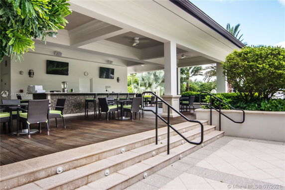 Outdoor lounge area with tables and chairs under a covered patio.