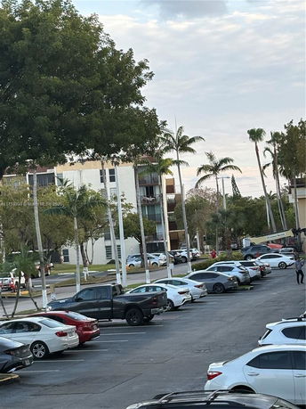 Outdoor parking area with several parked cars and surrounding trees
