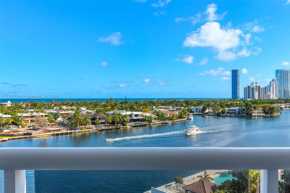 Panoramic view of waterfront properties, high-rise buildings, and ocean, seen from a balcony.