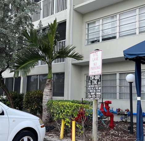 Exterior view of a multi-story building with large windows and a palm tree in front.