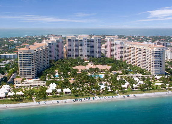 Aerial view of beachfront buildings with surrounding landscape and ocean.