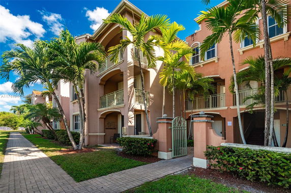 Front view of a multi-story building with balconies and palm trees.