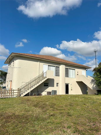 Front view of a two-story house with external staircases leading to the upper level.
