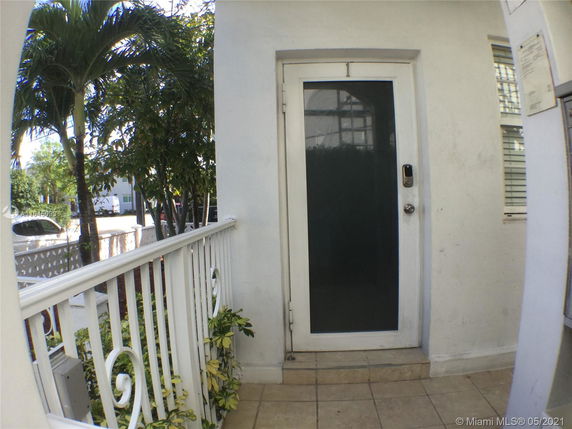 Entrance to a house with a white door and metal railing on a small porch.