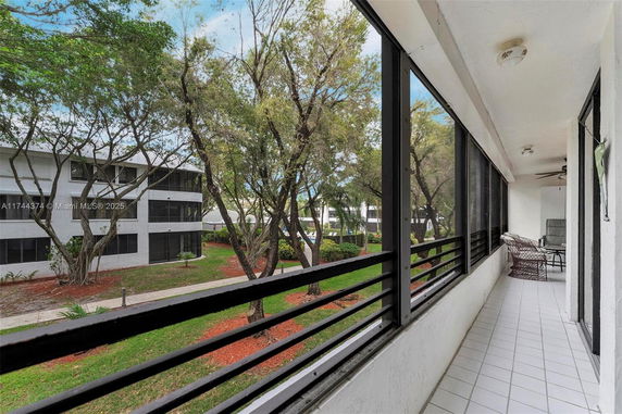 View of surrounding trees and a multi-story building from a balcony.
