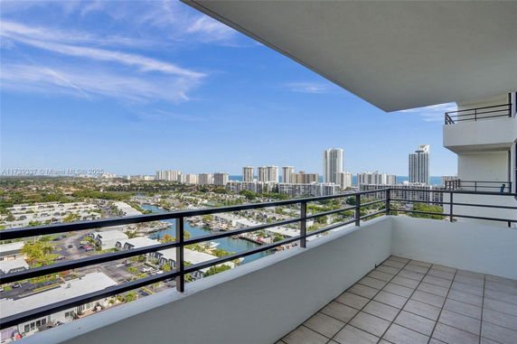 Panoramic view from a balcony overlooking a cityscape with high-rise buildings.