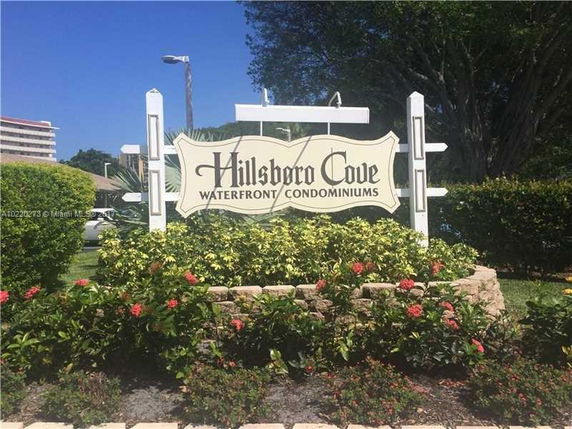 Signage for Hillsboro Cove Waterfront Condominiums surrounded by plants.