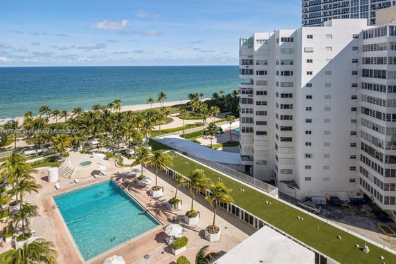 View from a building overlooking a swimming pool, landscaped area, and ocean.