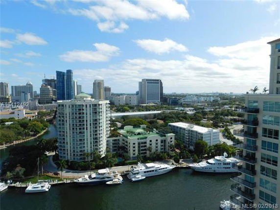 Panoramic view of a waterfront cityscape with high-rise buildings and boats.