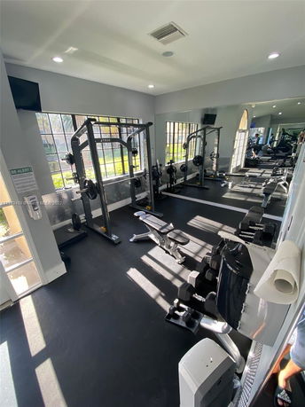 Indoor gym with exercise equipment including weights and benches.