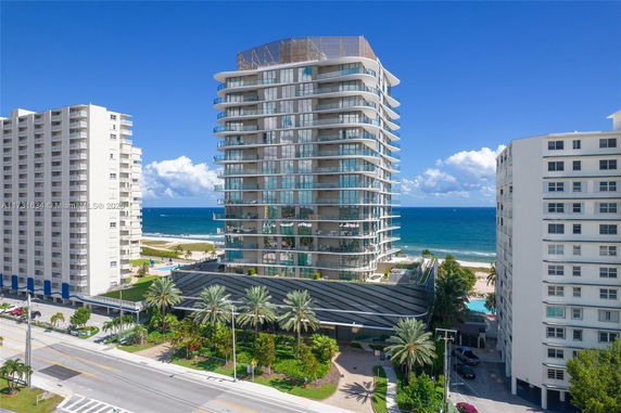 Front view of a modern high-rise beachfront building with glass balconies.