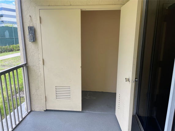 Open closet on a balcony with a view of the surrounding grassy area and buildings.
