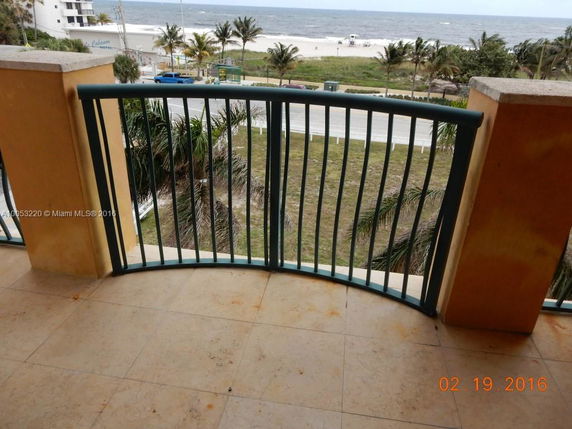 View from a balcony overlooking a beach and ocean.