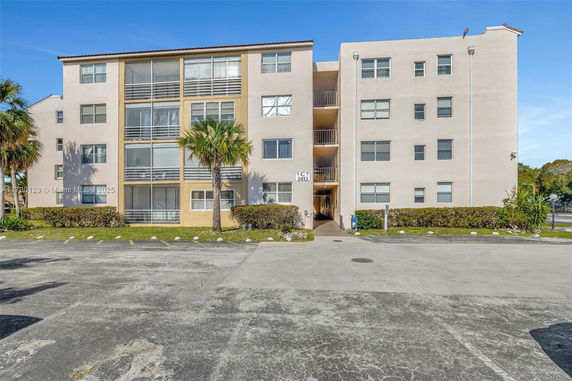 Front view of a multistory residential building with balconies and large windows.