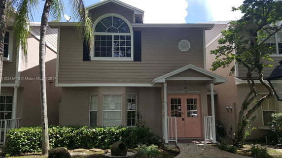 Front view of a two-story house with a distinctive arched window and a porch area.