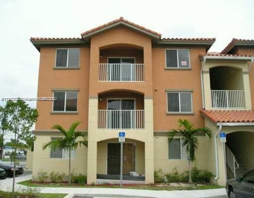 Front view of a three-story apartment building with balconies and a tiled roof.