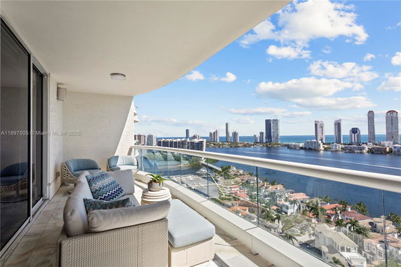Balcony with seating overlooking a cityscape and waterfront.