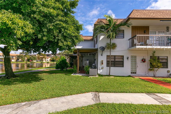 Front view of a two-story house with a small balcony and a grassy lawn.