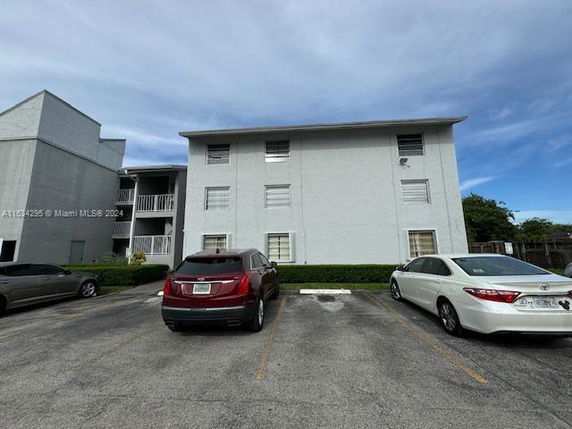 Outdoor parking area in front of a multi-story apartment building.