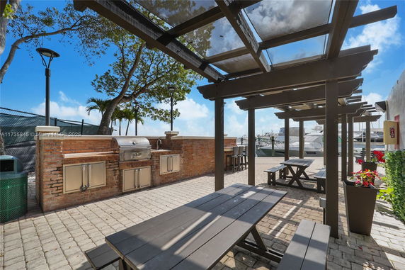 Outdoor area with picnic tables, pergola, and a built-in barbecue grill.
