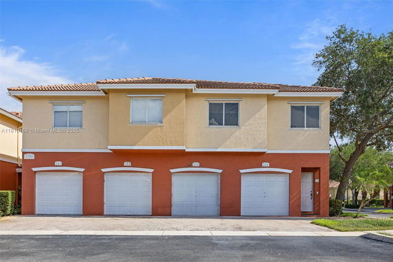 Front view of a two-story building with multiple garages and a tiled roof.