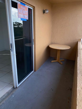 Small outdoor balcony with a round table and sliding glass door.