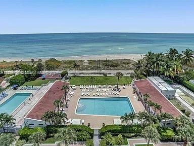 Aerial view of a swimming pool area with two adjacent pools next to a beach.