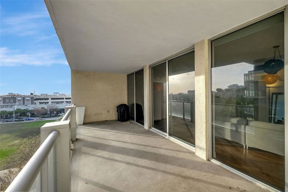 Balcony view overlooking an urban area with sliding glass doors opening to a living space.