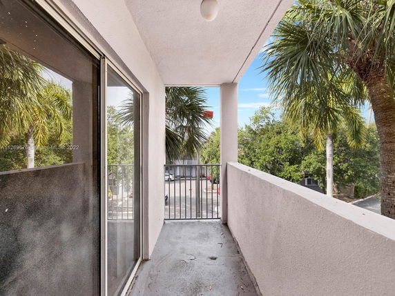 View from a balcony overlooking parking area and trees.