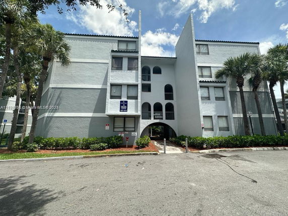 Front view of a multi-story residential building with arched entrances and windows.