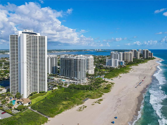 Aerial view of beachfront high-rise buildings along a sandy coastline.