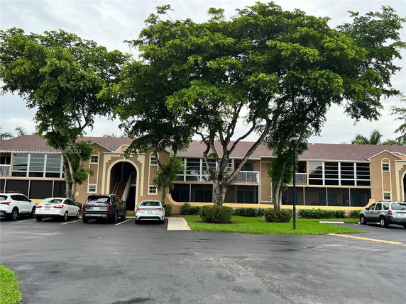 Front view of a two-story residential building with multiple entrances and parking area.