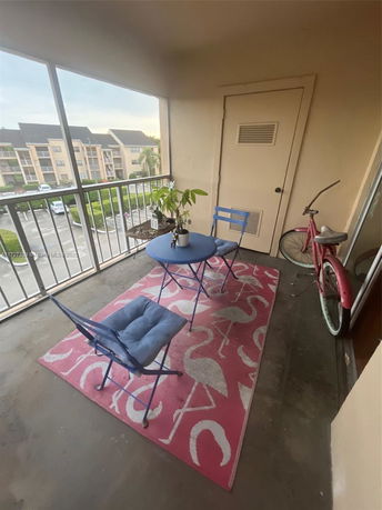 Balcony view overlooking residential buildings with a small table, chairs, and a bicycle.