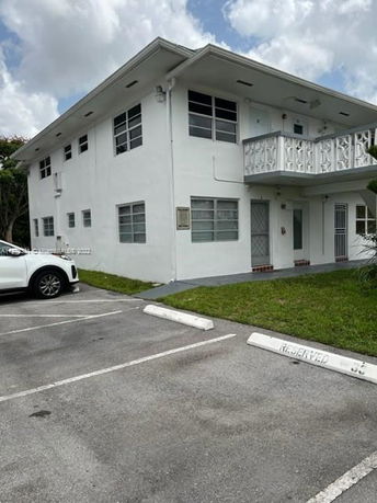 Two-story white building with parking area in front.