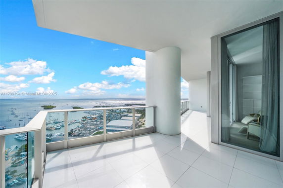 Panoramic view from a high-rise balcony overlooking a marina and ocean.