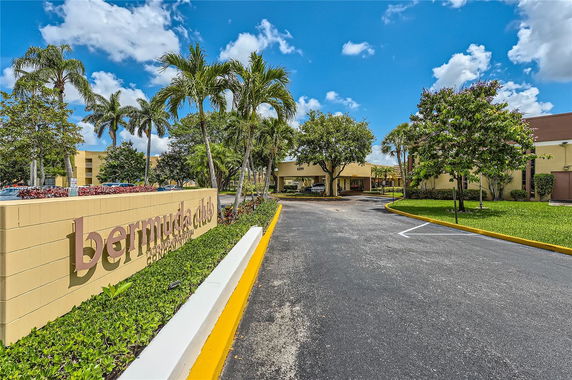 Front view of a building with 'Bermuda Club' sign and surrounding greenery.