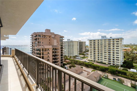 View from a balcony overlooking surrounding apartment buildings and a recreational area.