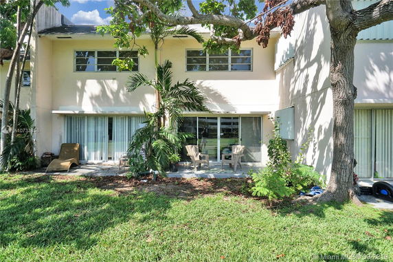 Front view of a two-story house with large glass sliding doors and outdoor seating area.