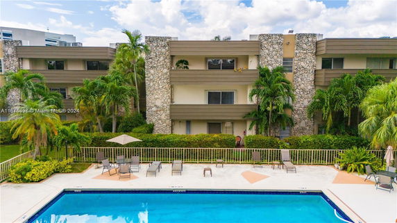 Front view of a multi-story building with stone accents and adjacent swimming pool.