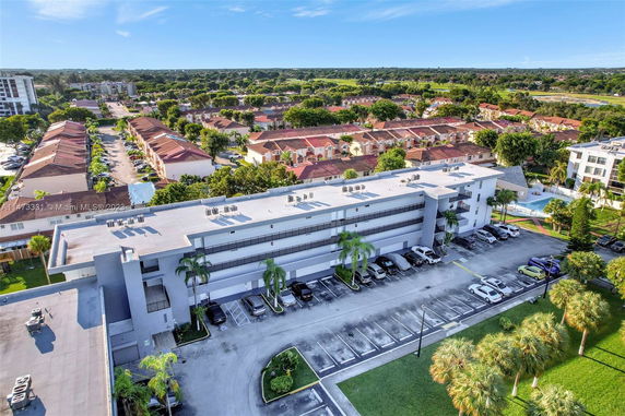 Aerial view of a multi-story building with a flat rooftop featuring several AC units.